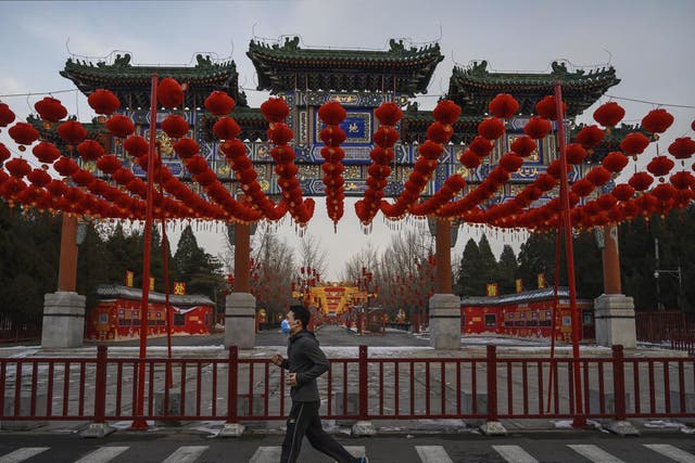 A man wears a protective mask as he runs past red lanterns at a cancelled Spring Festival event at a park on 8 February in Beijing, China