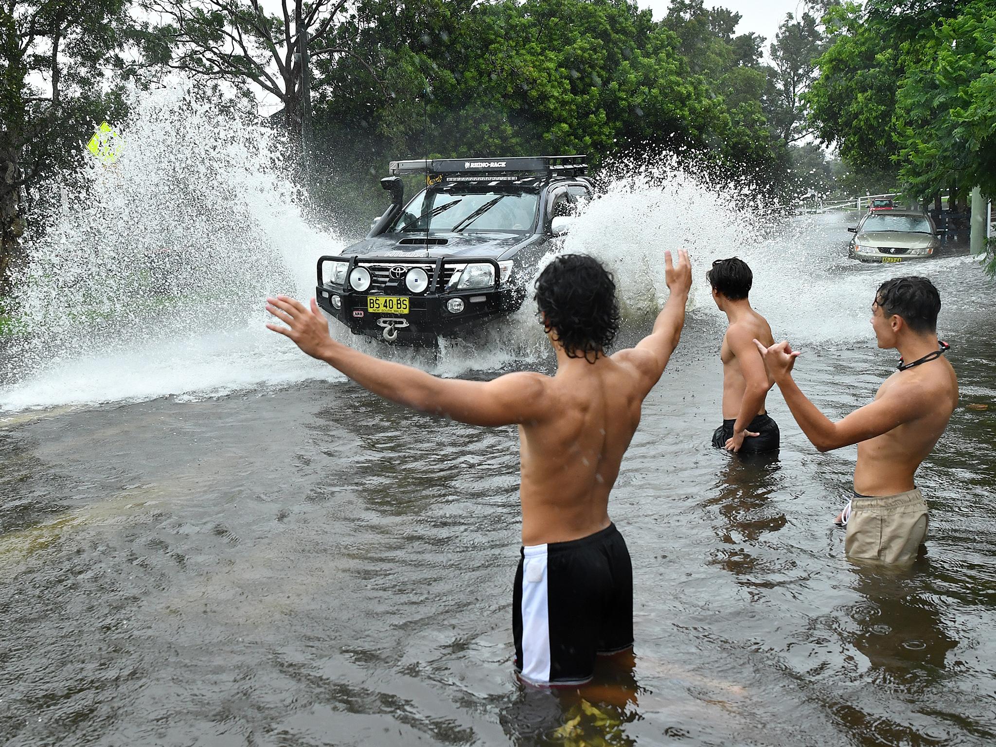 A group of young men direct traffic through floodwater in Sydney
