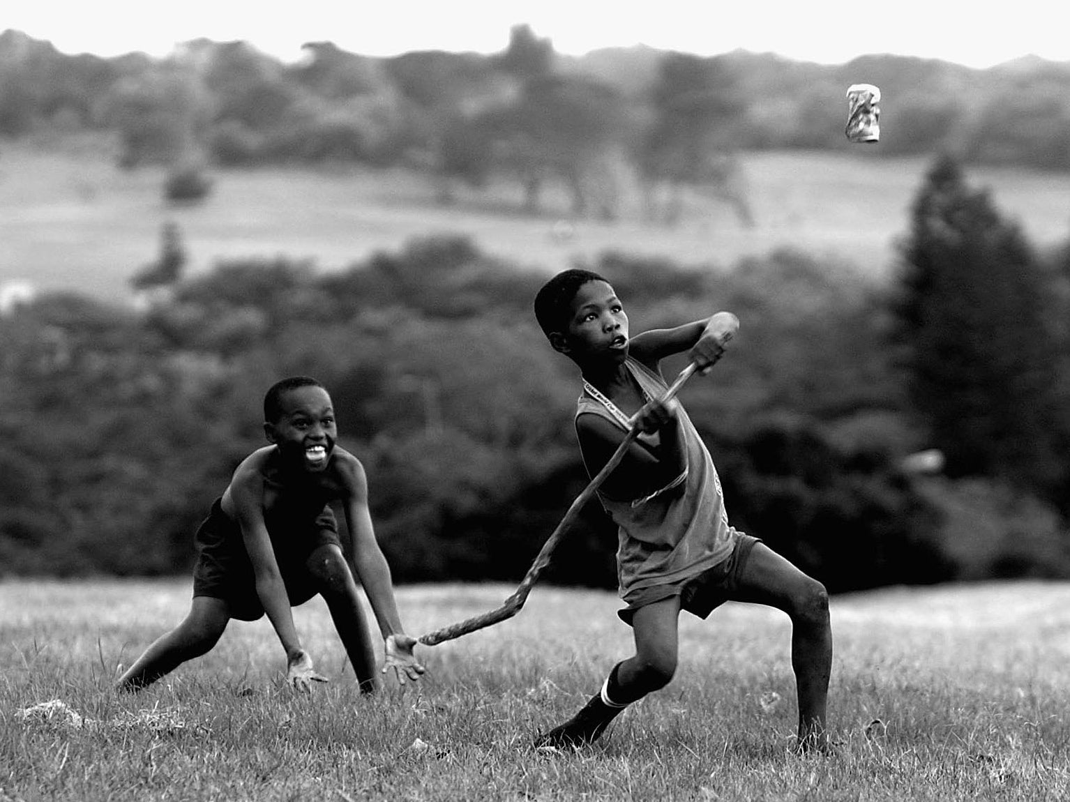 South African children playing cricket with a stick and a Coke can