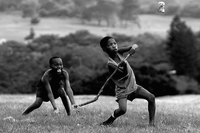 South African children playing cricket with a stick and a Coke can