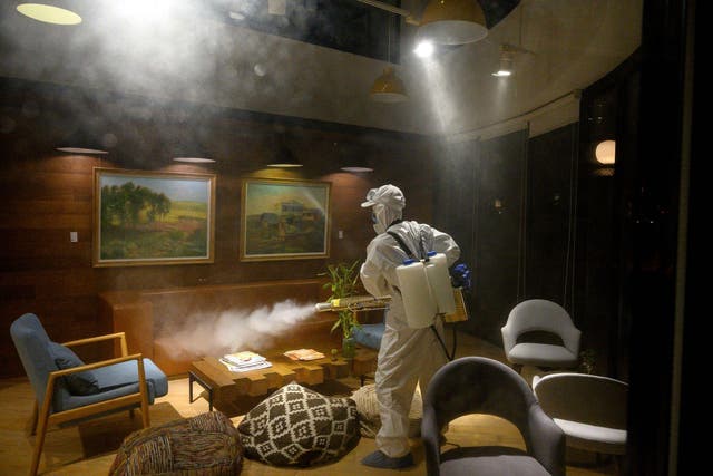 A worker wearing a protective suit uses a fogging machine to disinfect a business establishment in Shanghai on February 9, 2020