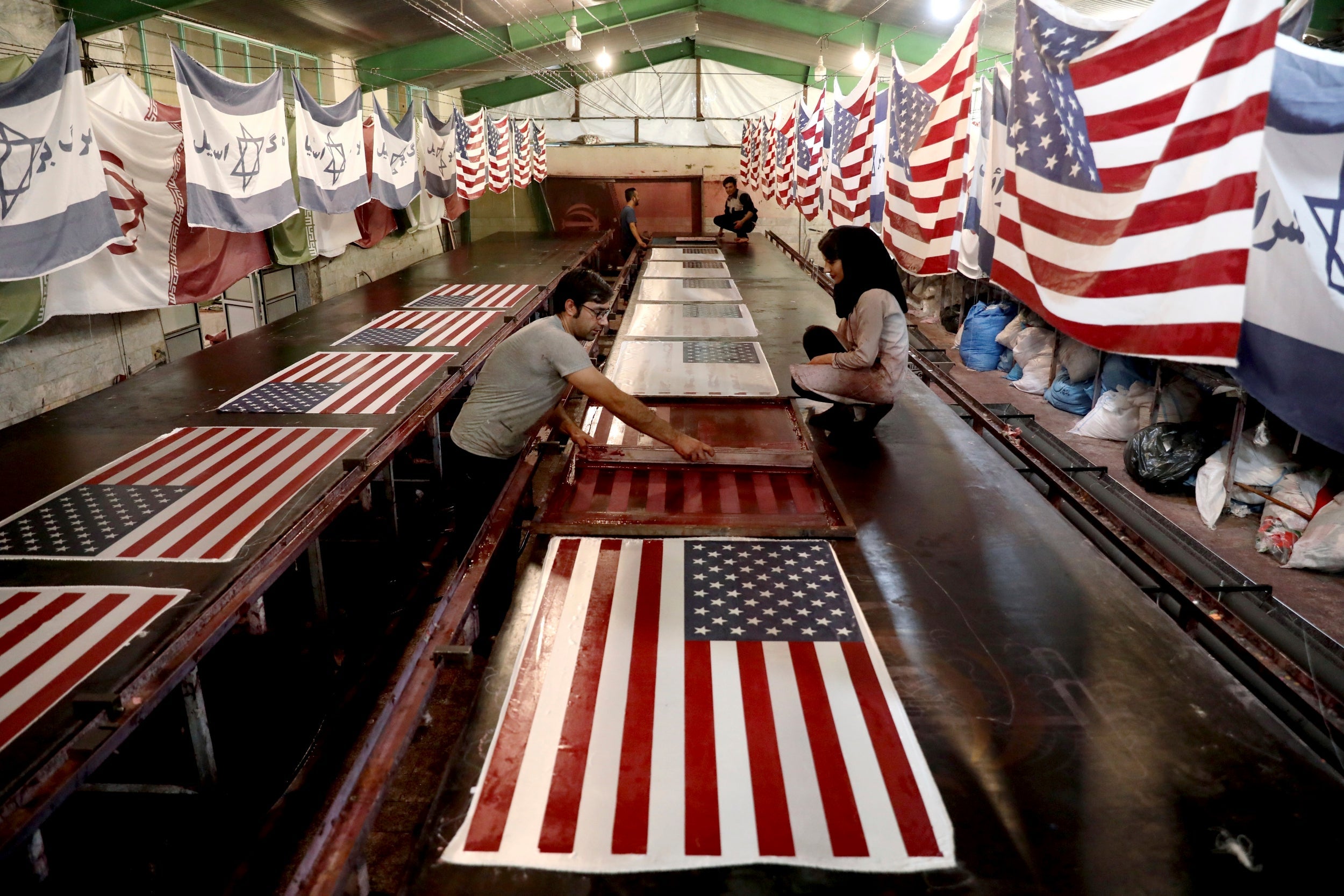 Workers print US flags using a silkscreen, at the Diba Parcham Khomein factory