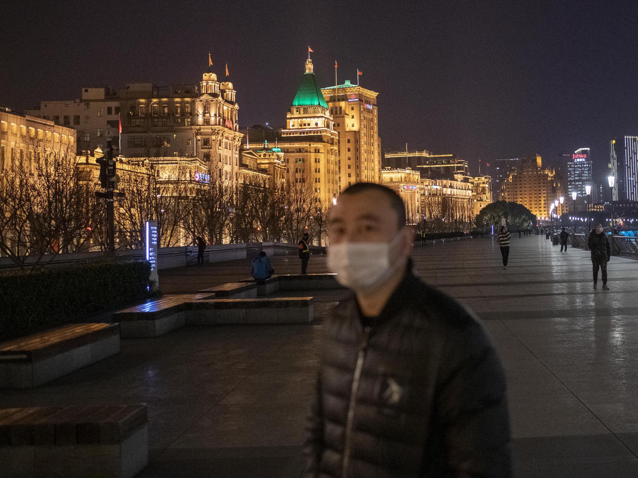 A man in a protective mask walks along a largely deserted Bund riverside promenade. Despite the fine weather and bright full moon, Shanghai residents mostly stayed indoors to avoid contagion from the coronavirus
