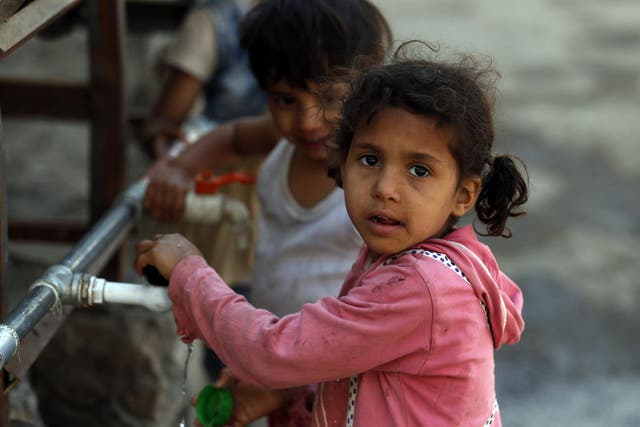 Displaced children drink water from a donated water tank in Sana’a, Yemen