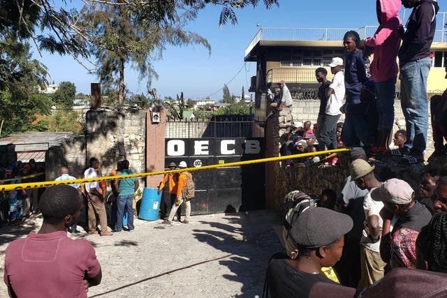 People stand outside the Orphanage of the Church of Bible Understanding where a fire broke out the previous night in the Kenscoff area outside Port-au-Prince, Haiti