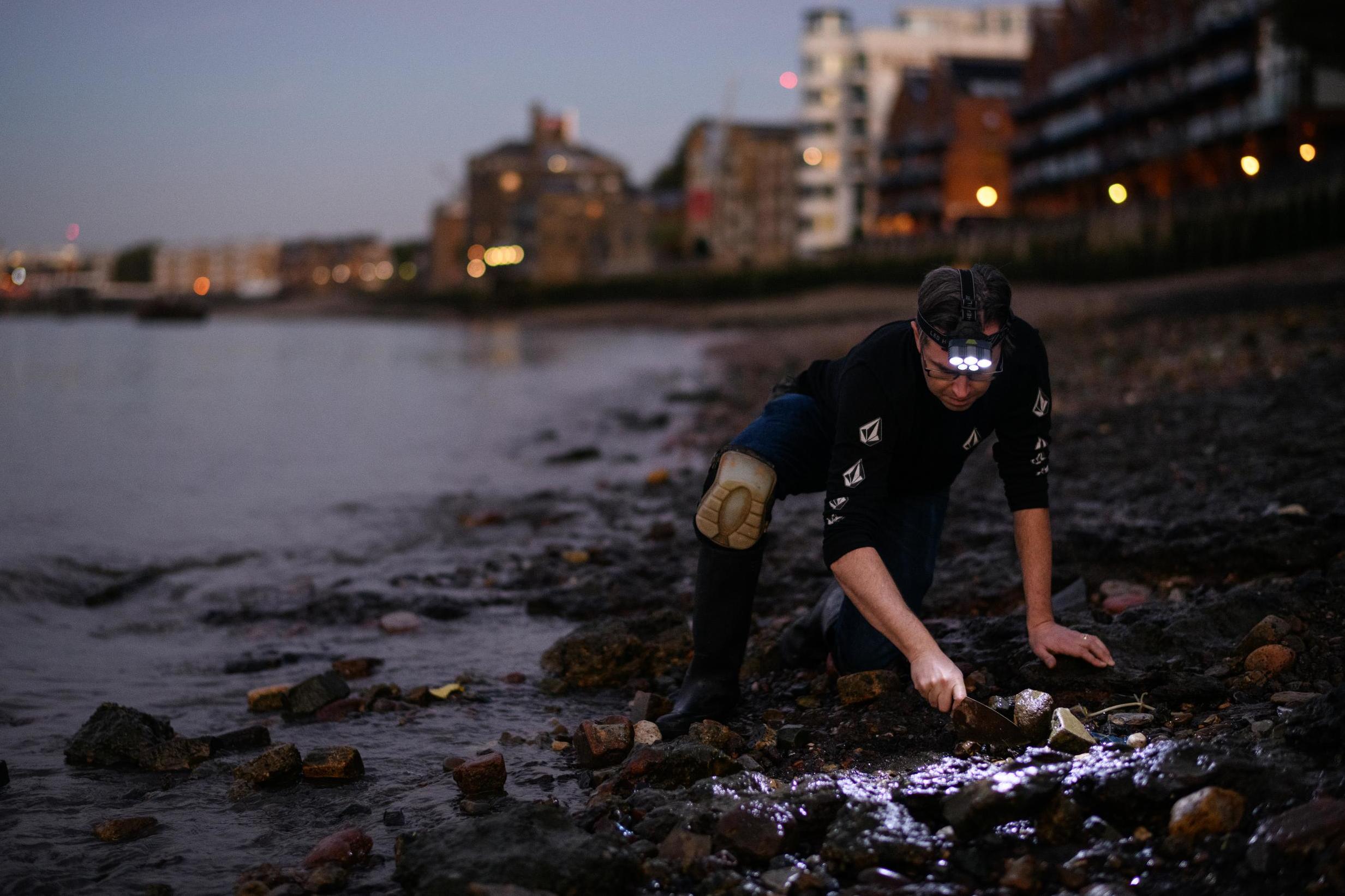 Jason Sandy uses a headtorch on an evening search of the Thames shoreline (Getty)