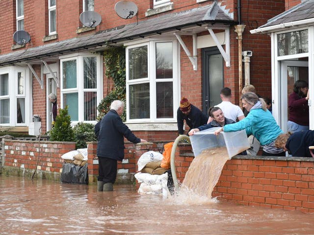 People bail water out of flooded homes after the River Wye burst its banks in Ross-on-Wye, western England
