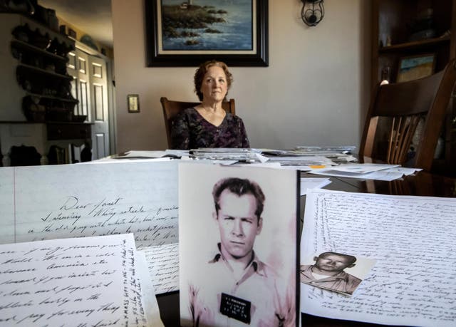 Janet Uhlar sits for a photo at her dining room table with an arrangement of letters and pictures she received through her correspondence with imprisoned Boston organized crime boss James "Whitey" Bulger, Friday, Jan. 31, 2020, in Eastham, Mass. Uhlar was one of 12 jurors who found Bulger guilty in a massive racketeering case, including involvement in 11 murders. But now she says she regrets voting to convict Bulger on the murder charges, because she learned he was an unwitting participant in a secret CIA experiment in which he was dosed with LSD on a regular basis for 15 months.
