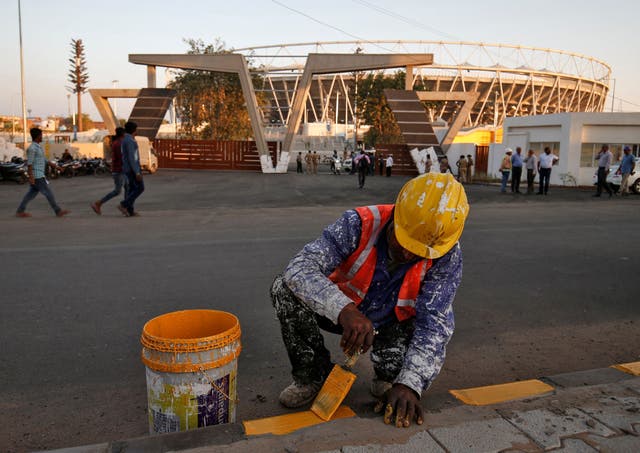 A worker paints a footpath in front of Sardar Patel Gujarat Stadium, where Donald Trump is expected to visit during his upcoming trip to India, in Ahmedabad