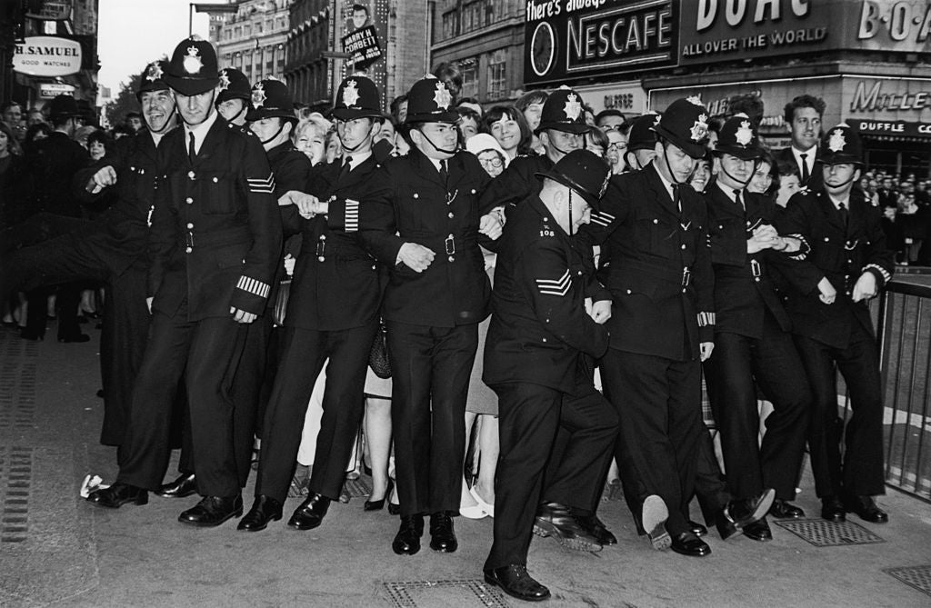 Policemen form a line to restrain female fans during the premiere of the new Beatles film ‘Help!’ at the London Pavilion, Piccadilly Circus, 29 July 1965