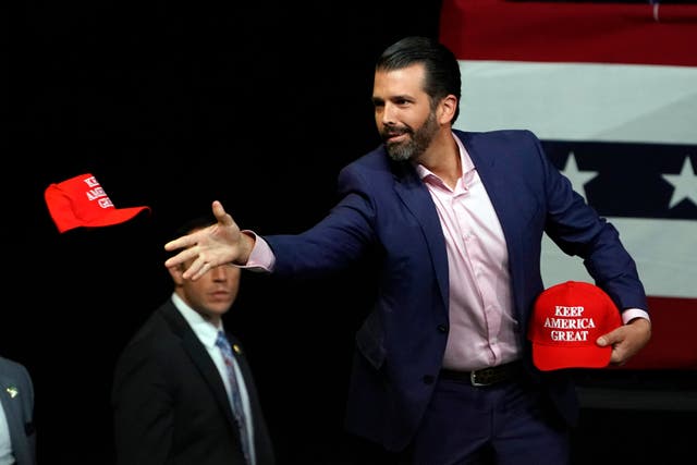 Donald Trump Jr distributes Keep America Great caps at a rally by his father in Phoenix, Arizona