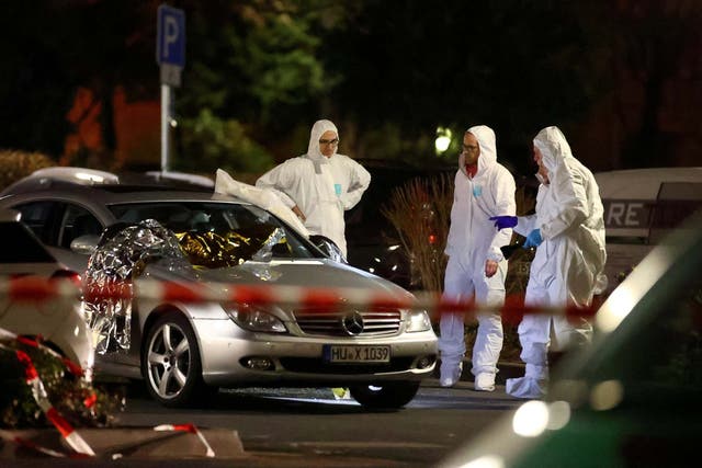 Forensic experts work around a damaged car after a shooting in Hanau