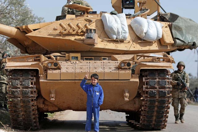 A Syrian boy stands in front of a Turkish military vehicle east of Idlib city in northwestern Syria on February 20, 2020