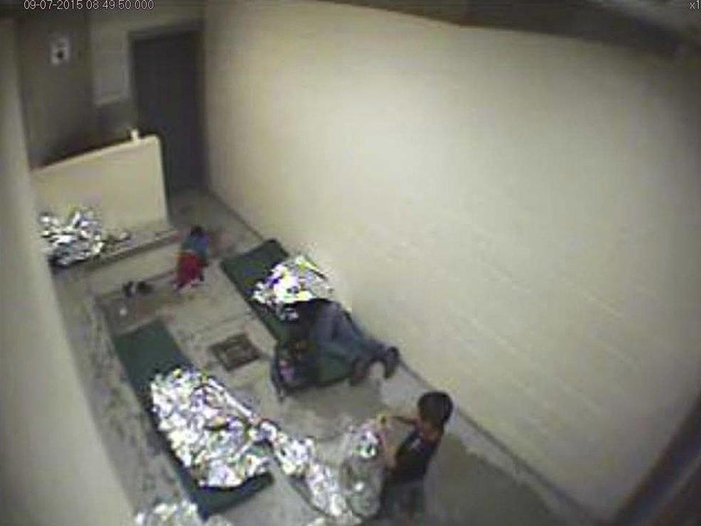 An image from US Border Patrol surveillance video shows a child crawling on the concrete floor near the bathroom area of a holding cell in Douglas Arizona, 2015