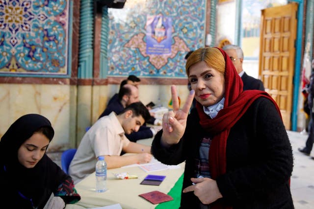 A voter flashes the victory sign after casting her ballot at a Tehran polling station on Friday