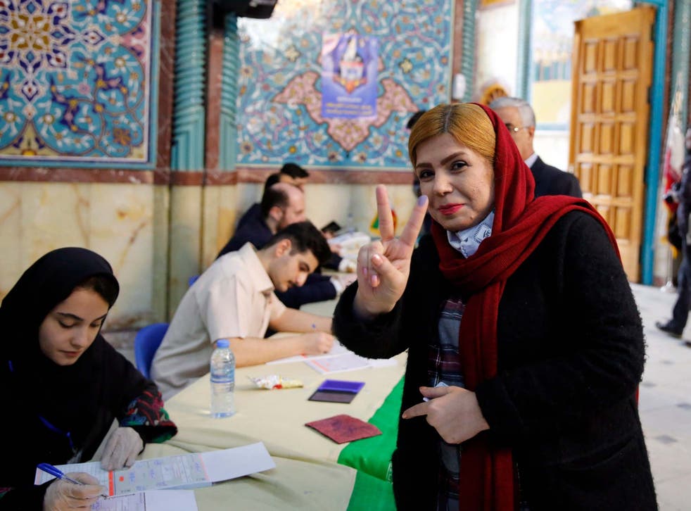 A voter flashes the victory sign after casting her ballot at a Tehran polling station on Friday