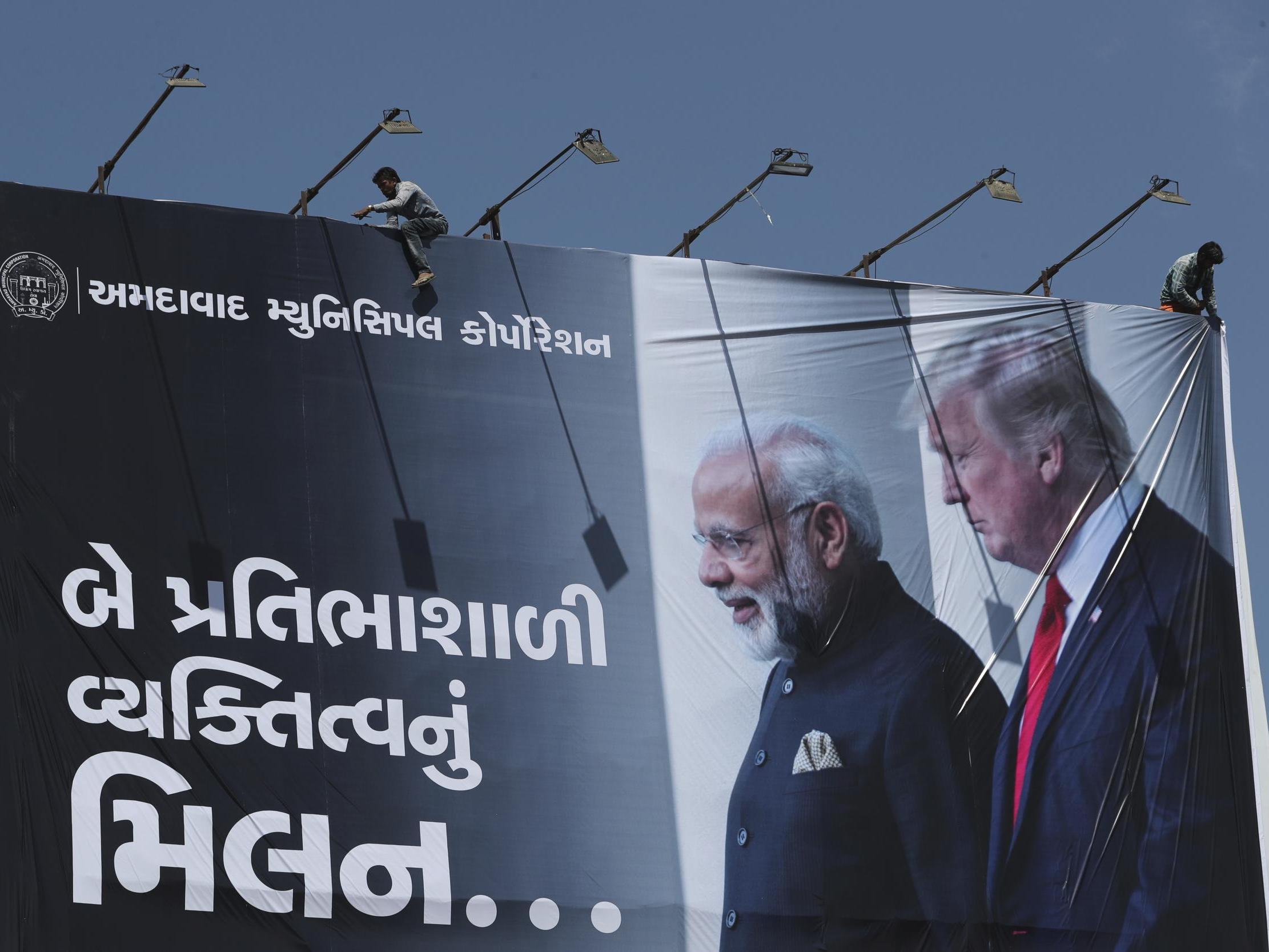An Indian worker installs a giant hoarding welcoming US President Donald Trump ahead of his visit, in Ahmadabad, India
