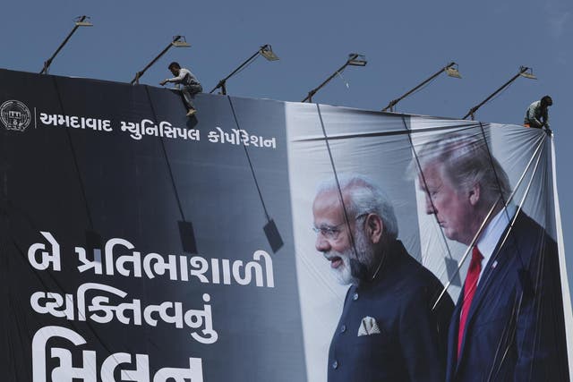 An Indian worker installs a giant hoarding welcoming US President Donald Trump ahead of his visit, in Ahmadabad, India