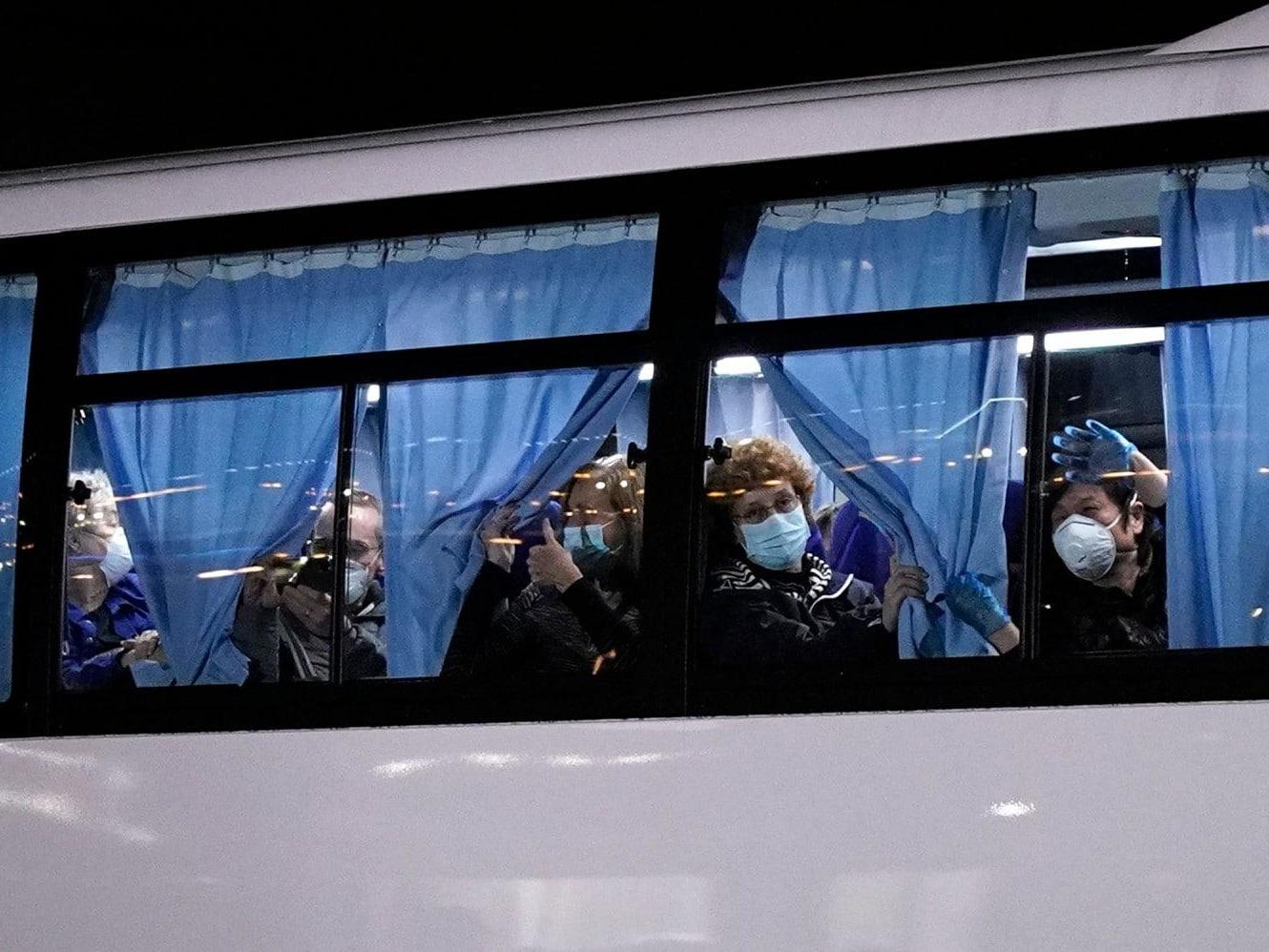 US citizens wave from a bus 17 February 2020 as they leave the Diamond Princess cruise ship docked in Yokohama, Japan