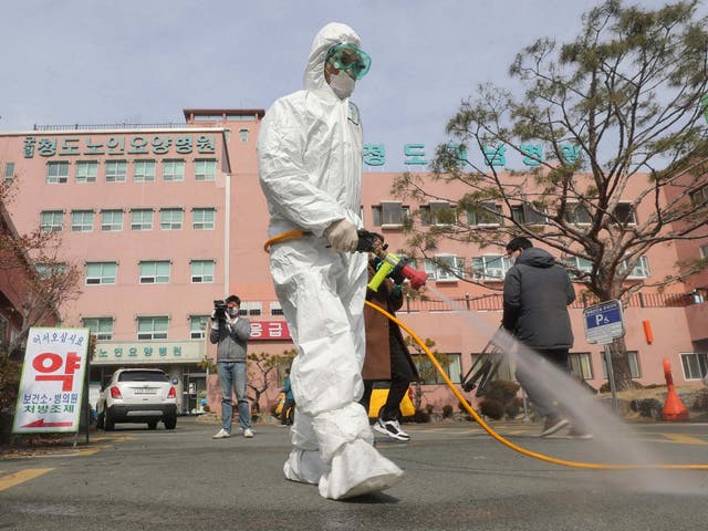 A worker wearing protective gears sprays disinfectant against the coronavirus in front of the Daenam Hospital in Cheongdo, where a 'special care zone' has been declared