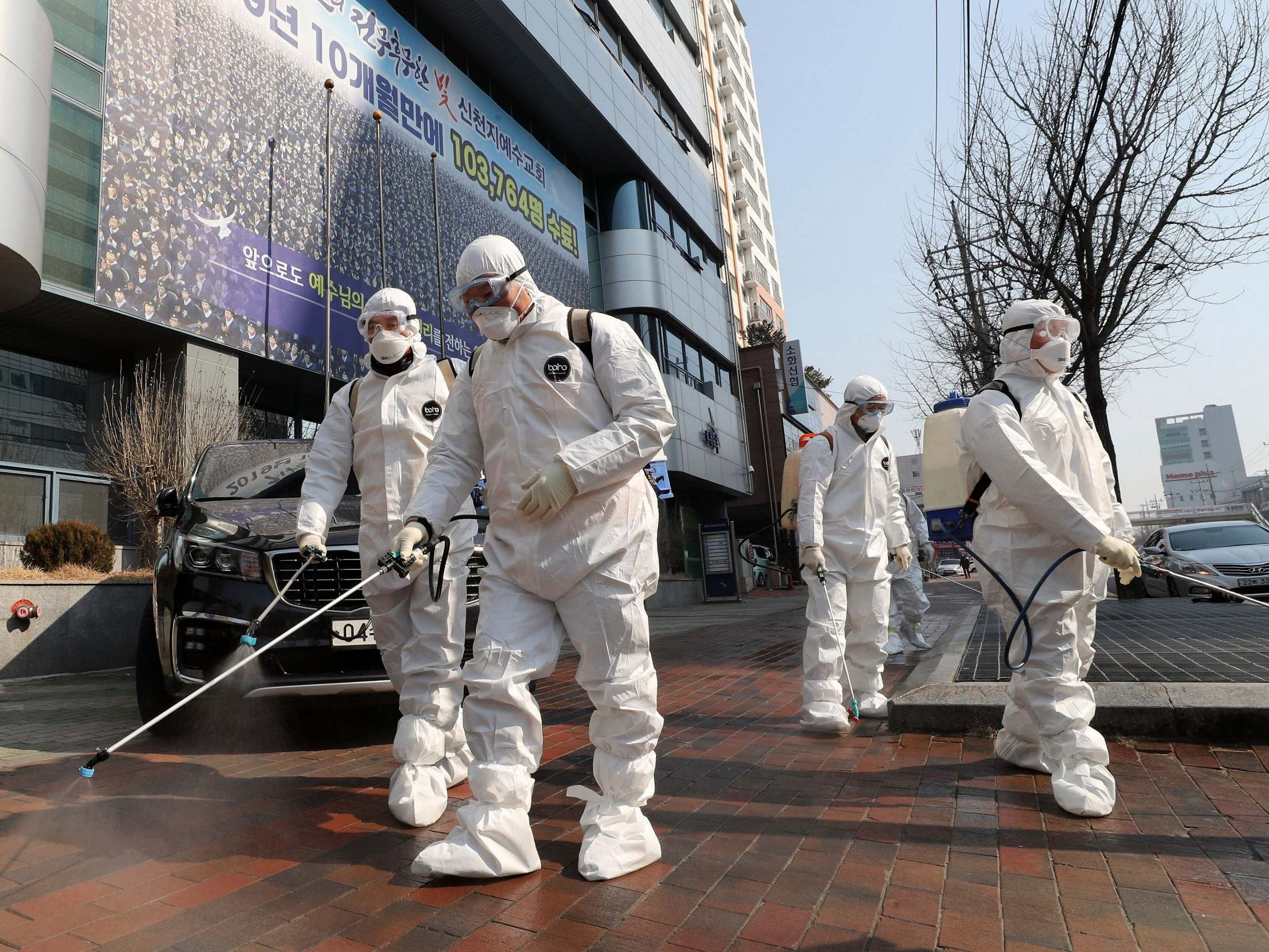 Workers wearing protective gears spray disinfectant on Daegu's deserted streets