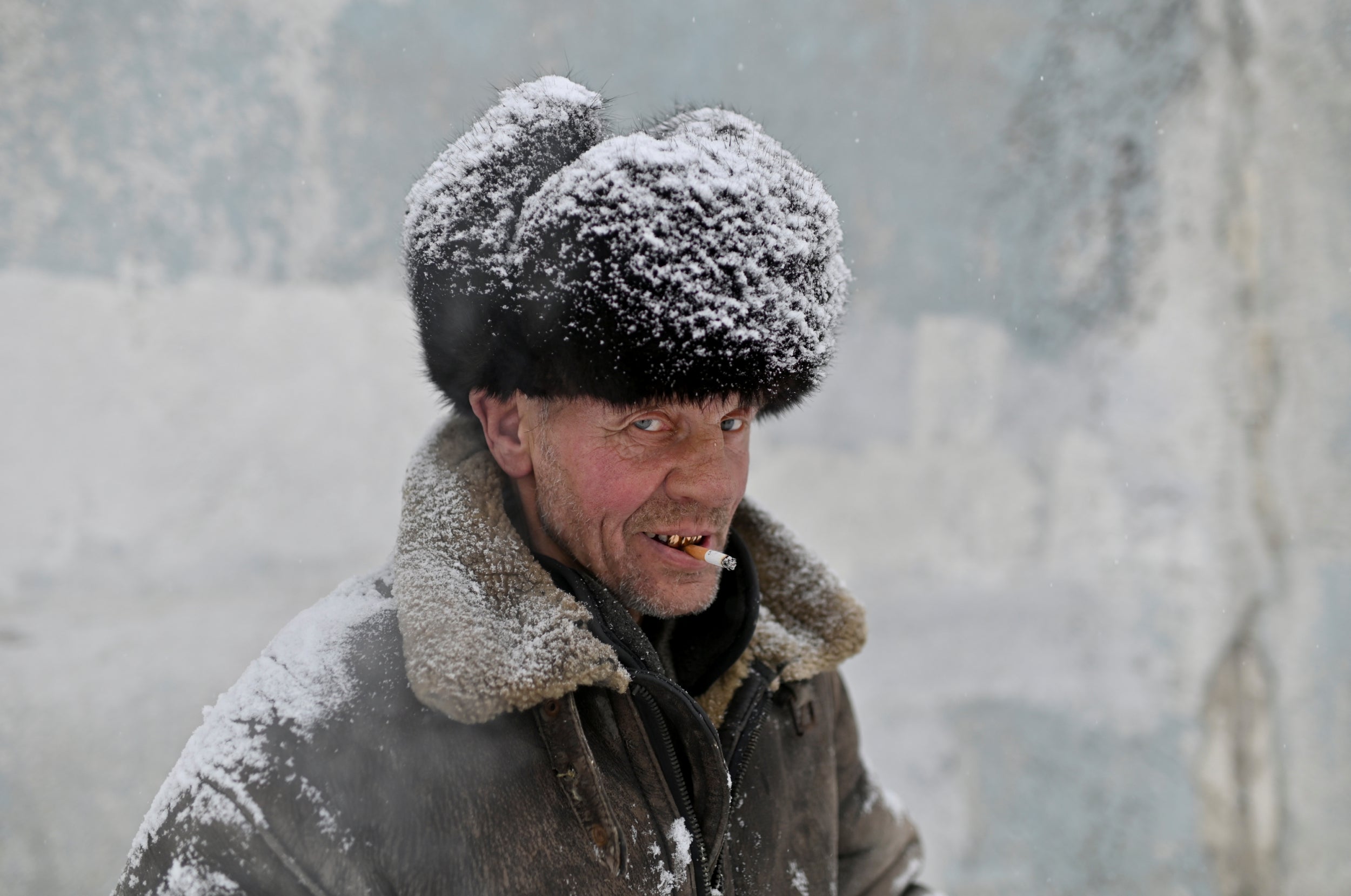 A man who is homeless smokes a cigarette as he attends a charity event organised by Caritas, a Catholic organisation, held to distribute food and present gifts to homeless and lower-income citizens during the Christmas period