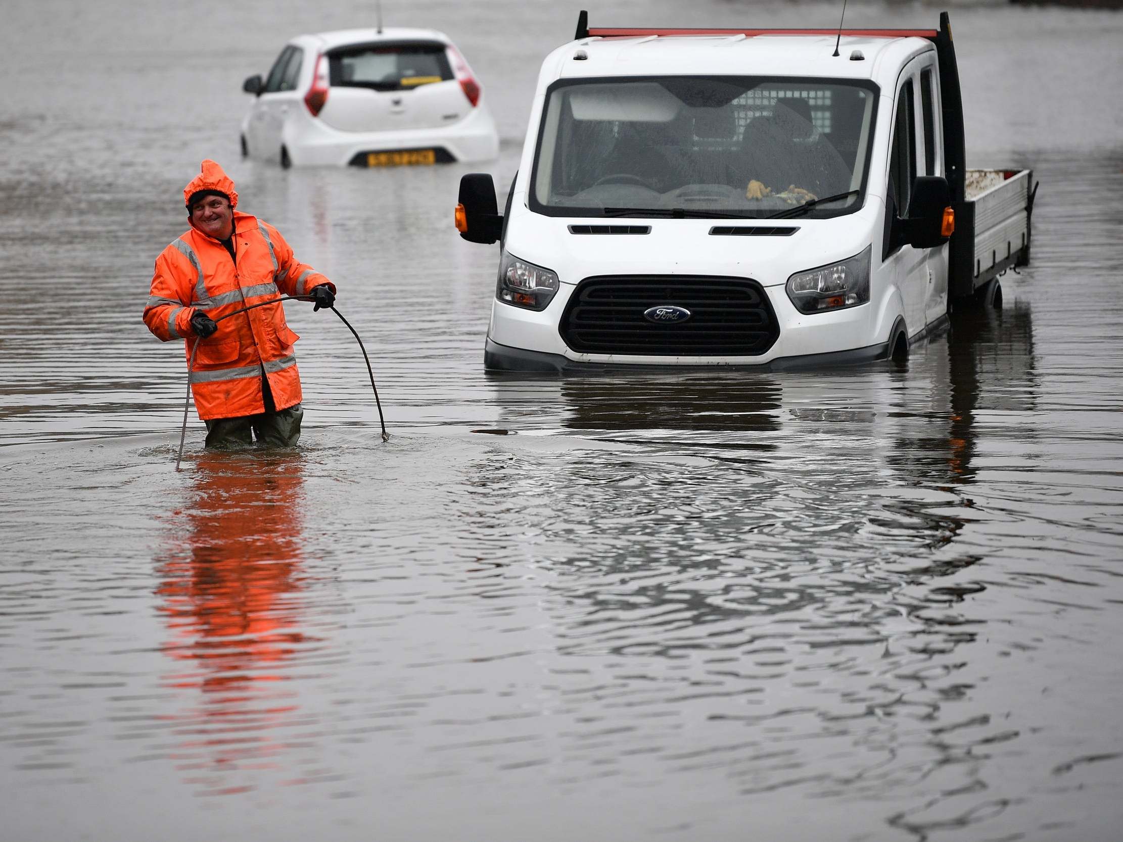 A worker recovers stranded vehicles from flood water on the A761 in Paisley, Scotland