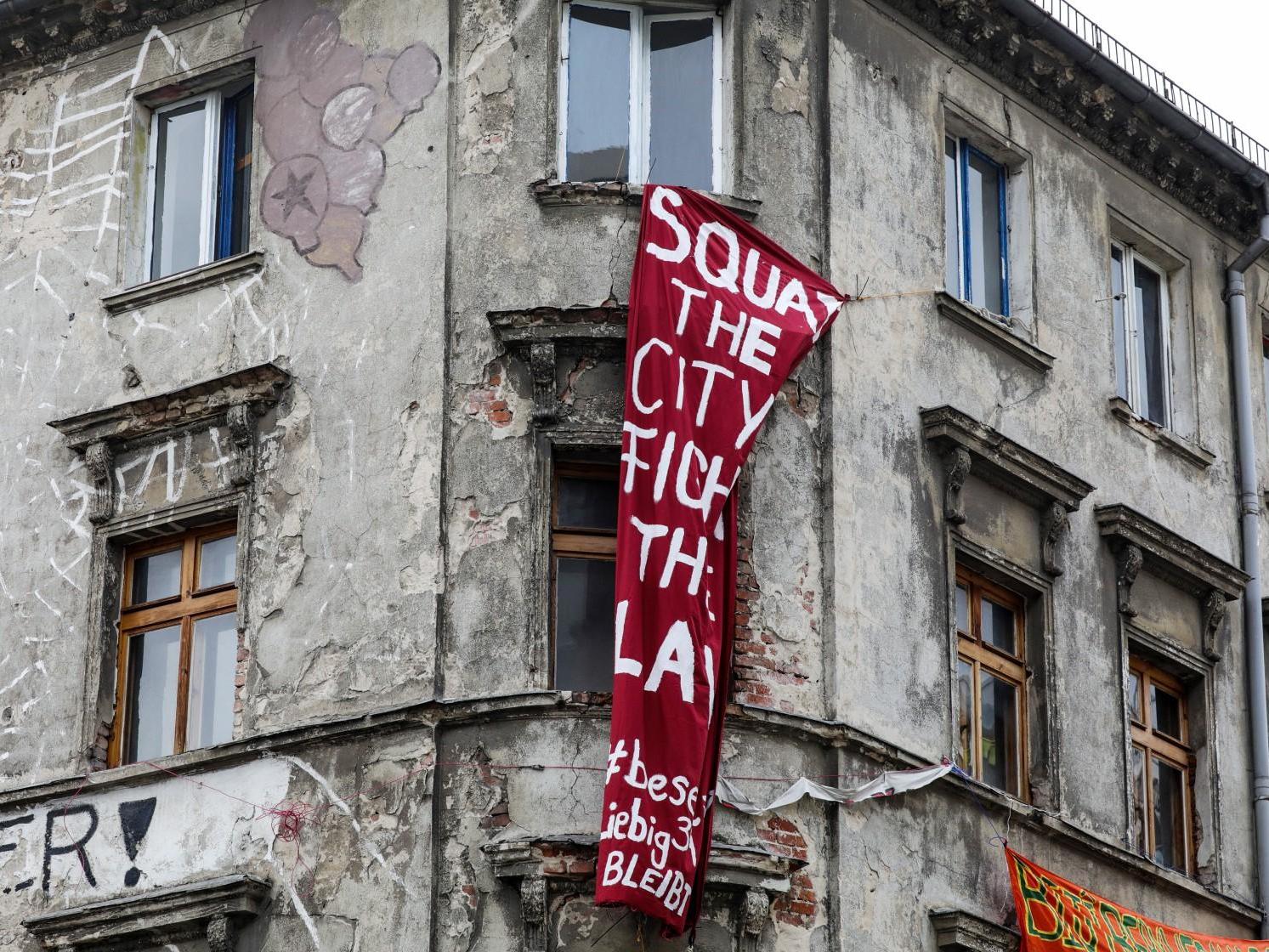 A banner reading 'Squat the city' hangs on an abandoned building in Berlin amid growing anger over the lack of affordable living space