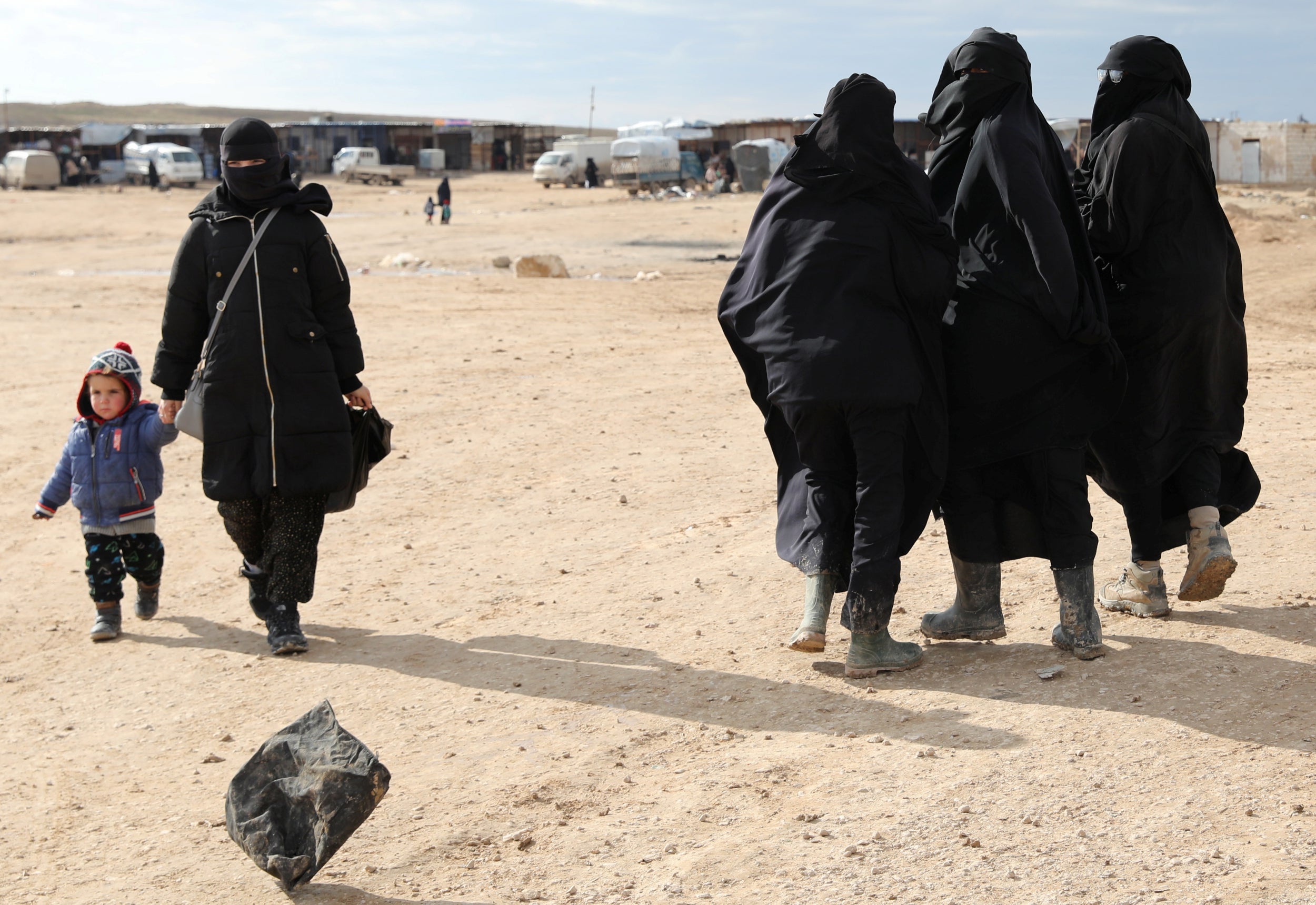 A woman holds hands with a child while walking through al-Hol camp, Syria, in January