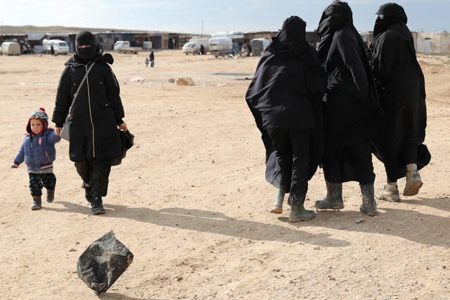 A woman holds hands with a child while walking through al-Hol camp, Syria, in January