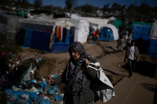Elderly woman makes her way at a makeshift camp surrounding the Moria migrant camp
