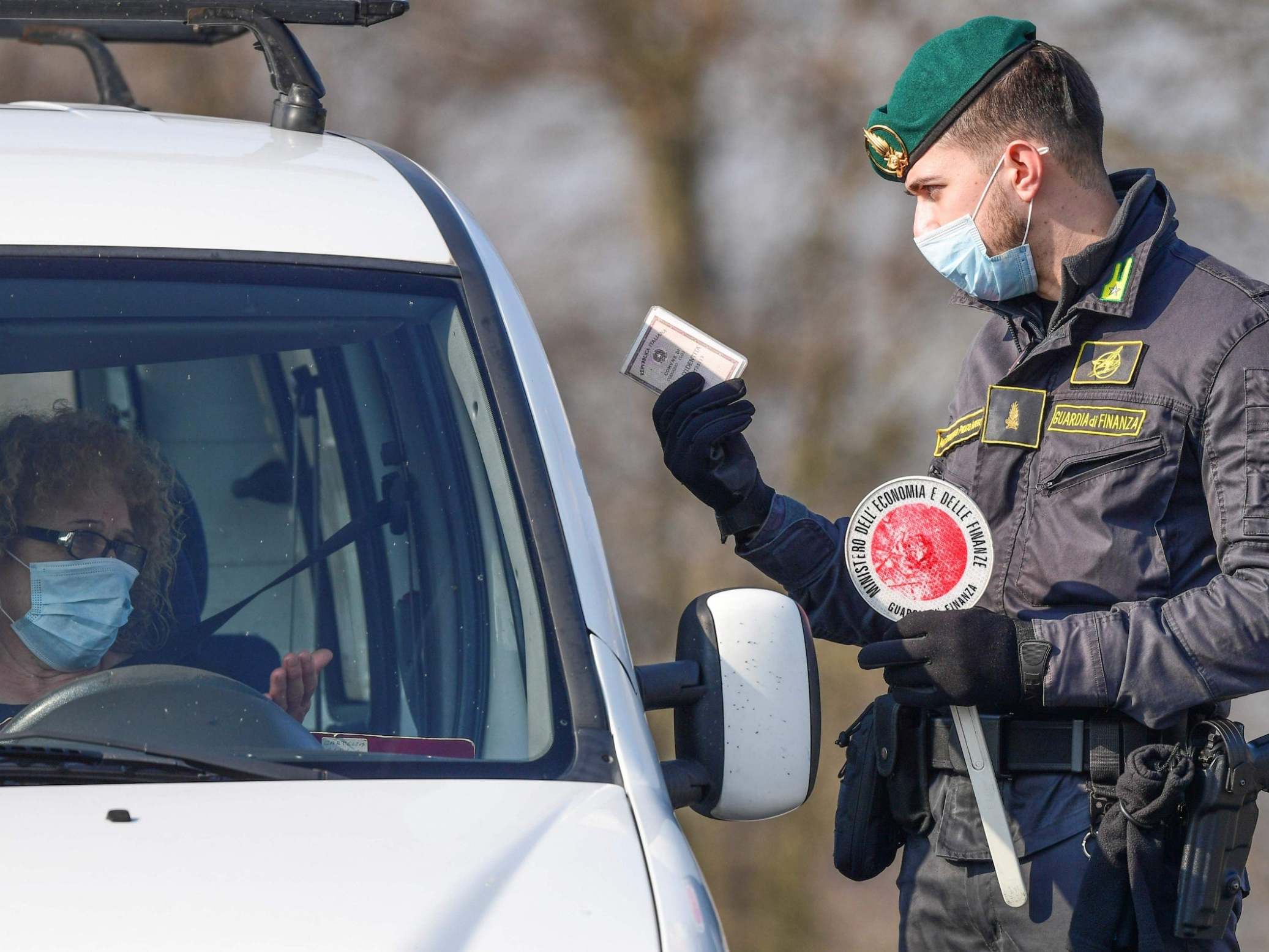 A guard talks to a driver at a checkpoint in Zorlesco, southeast of Milan