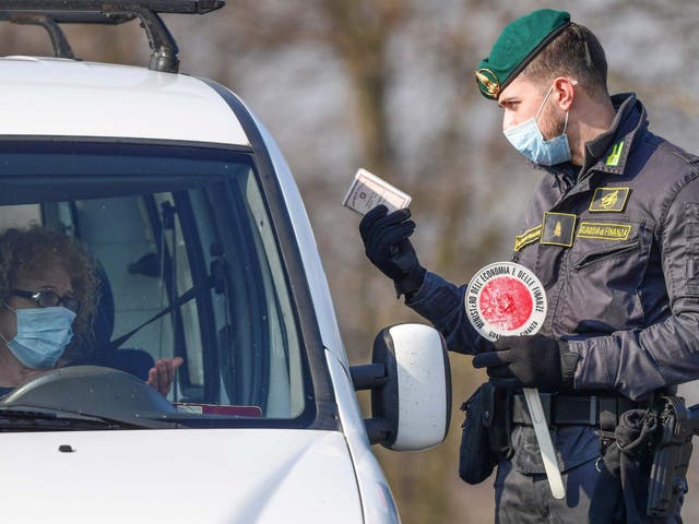 A guard talks to a driver at a checkpoint in Zorlesco, southeast of Milan