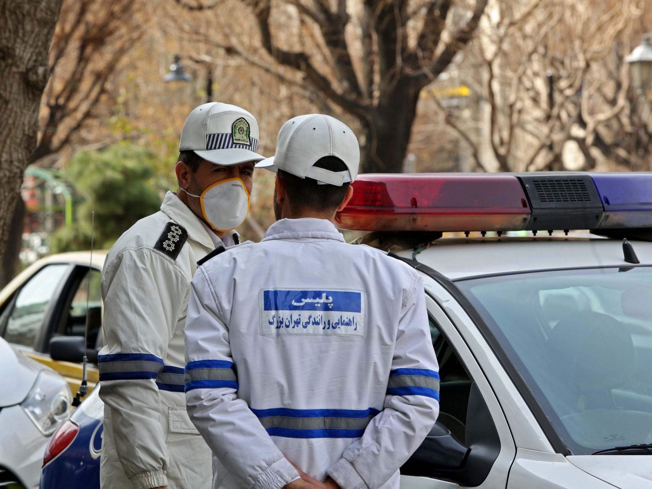 Emergency first responders wear protective masks stand in Tehran