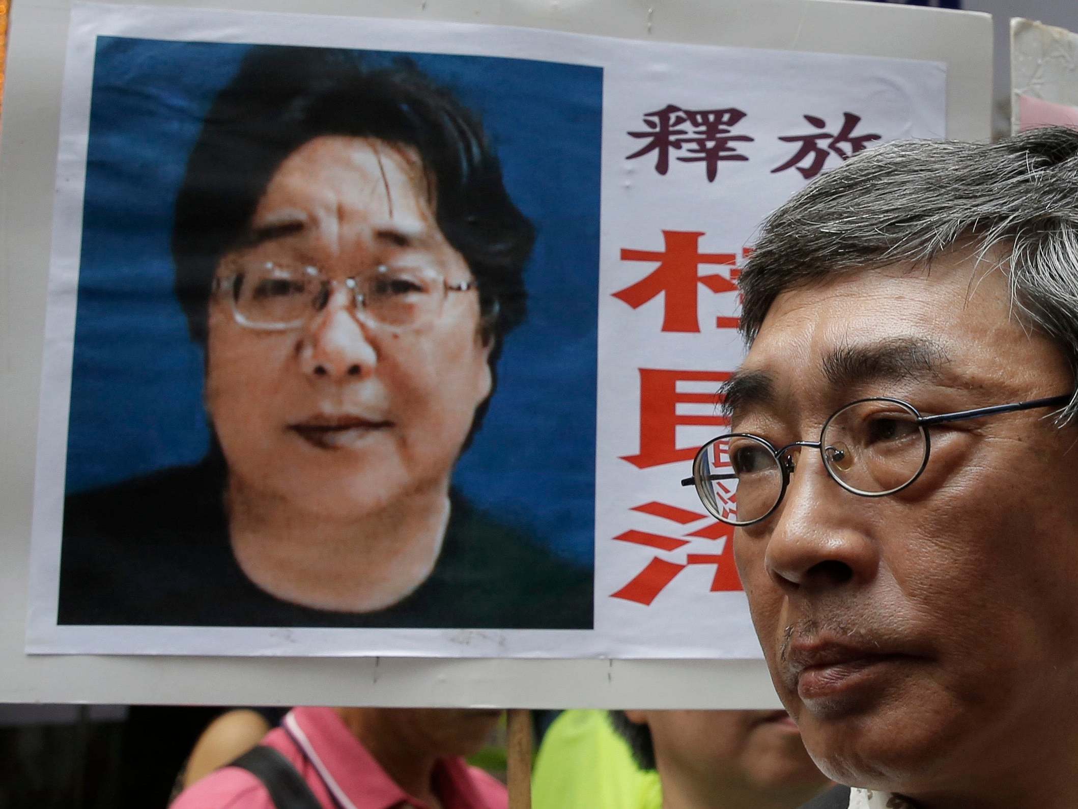 A picture of missing bookseller Gui Minhai is shown on a placard beside freed Hong Kong bookseller Lam Wing-kee, as the protesters are marching to the Chinese central government's liaison office in Hong Kong