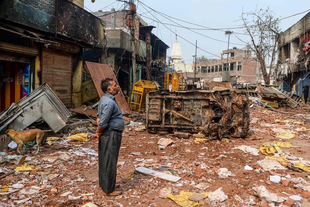 A resident stands by burned-out and damaged homes and shops following clashes in Delhi on Wednesday