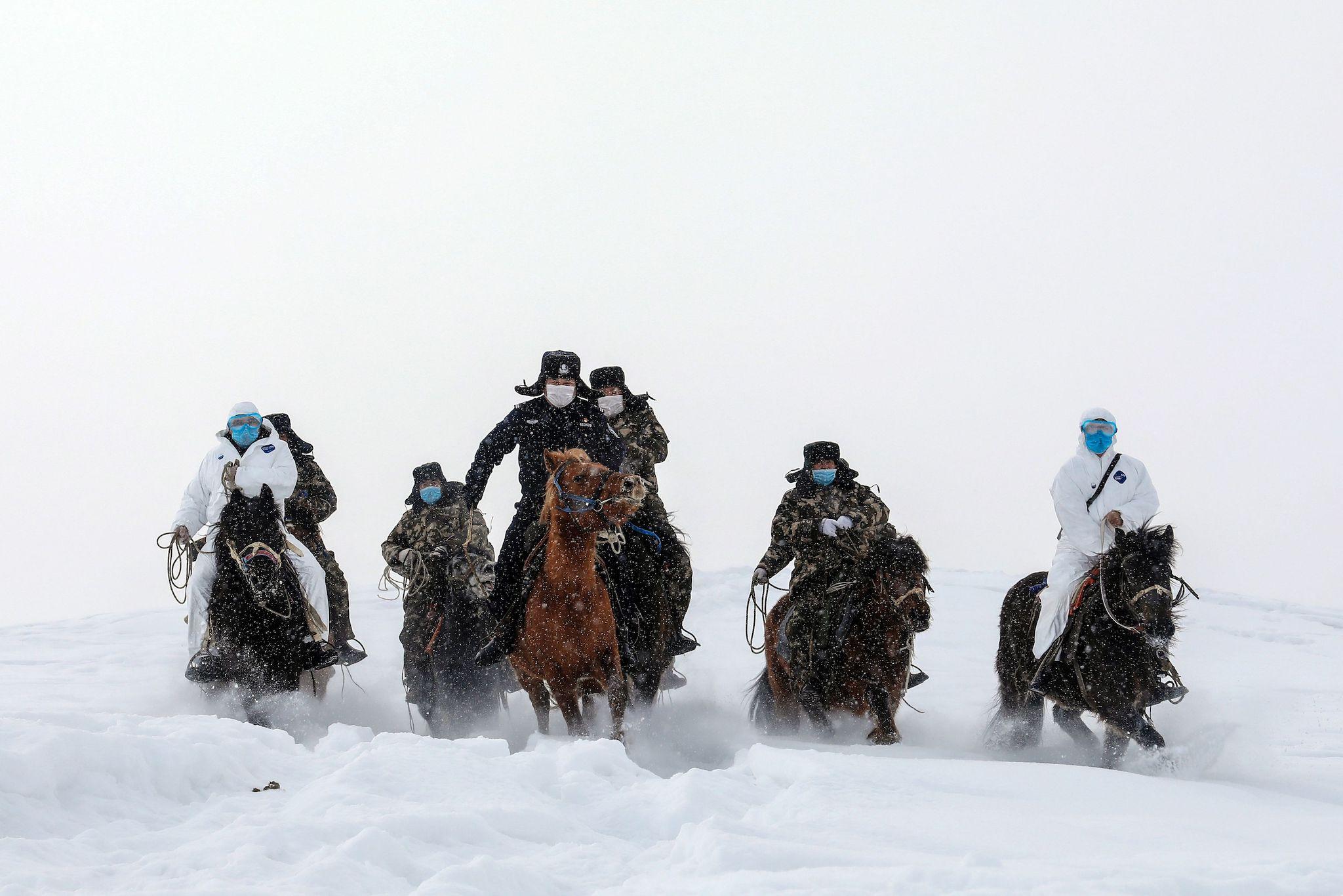This photo taken on February 19, 2020 shows police officers wearing protective face masks riding horses on their way to visit residents who live in remote areas in Altay, farwest China's Xinjiang region, to promote the awareness of the virus