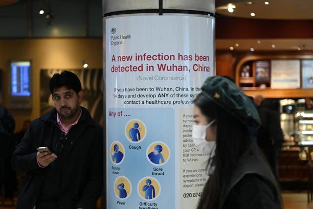 A woman wearing a face mask passes a Public Health England sign at London Heathrow Airport, the busiest airport in Europe, on 28 January 2020