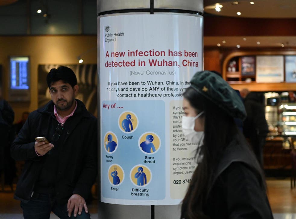 A woman wearing a face mask passes a Public Health England sign at London Heathrow Airport, the busiest airport in Europe, on 28 January 2020