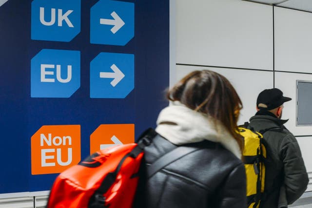 Passengers walk past sign prior to immigration control pointing towards queues for UK, EU and Non-EU passport holders