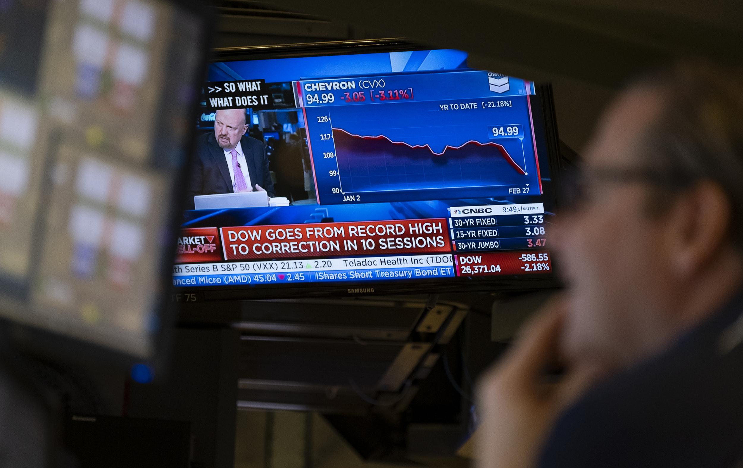 Stocks reflect declines on monitors as people work on the floor of the New York Stock Exchange on Thursday, 27 February, 2020