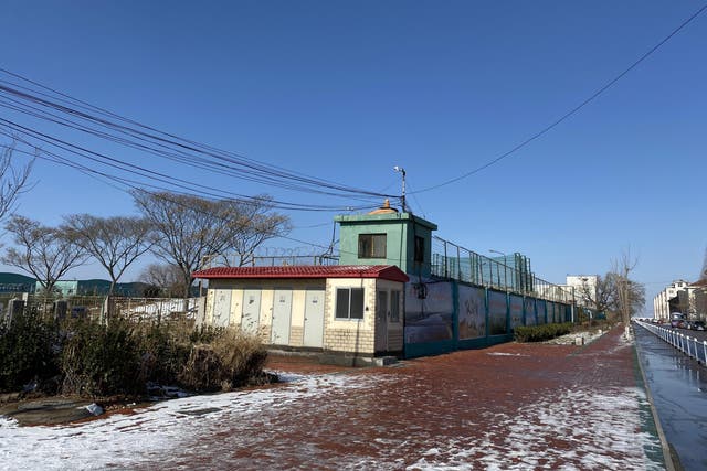 The fences along the side of the Qingdao Taekwang Shoes Co. factory include watchtowers with cameras pointed in all directions and high barbed-wire fences atop the walls