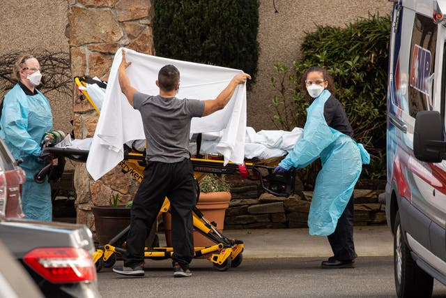 Healthcare workers transfer a patient at the Life Care Center in Kirkland, Washington, into an ambulance as tests continue for the coronavirus