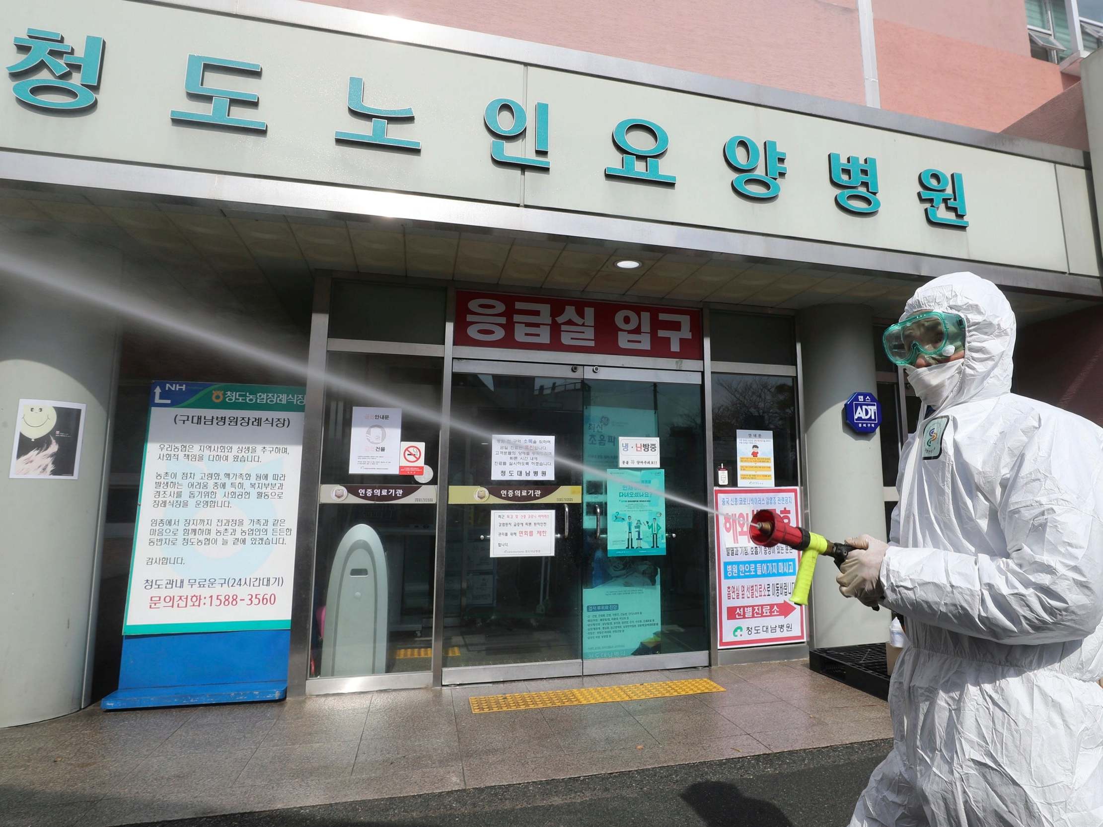 A worker wearing protective gears sprays disinfectant against the new coronavirus in front of the Daenam Hospital in Cheongdo, South Korea