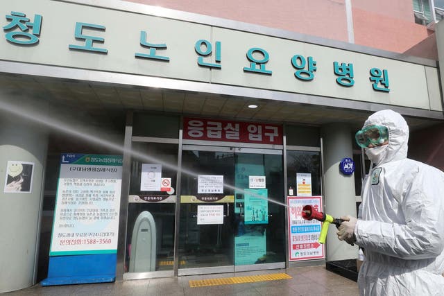 A worker wearing protective gears sprays disinfectant against the new coronavirus in front of the Daenam Hospital in Cheongdo, South Korea
