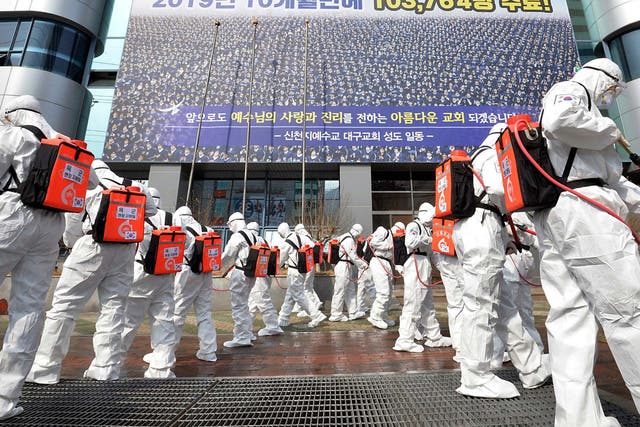 Army soldiers wearing protective suits spray disinfectant in front of a branch of the Shincheonji Church of Jesus in Daegu