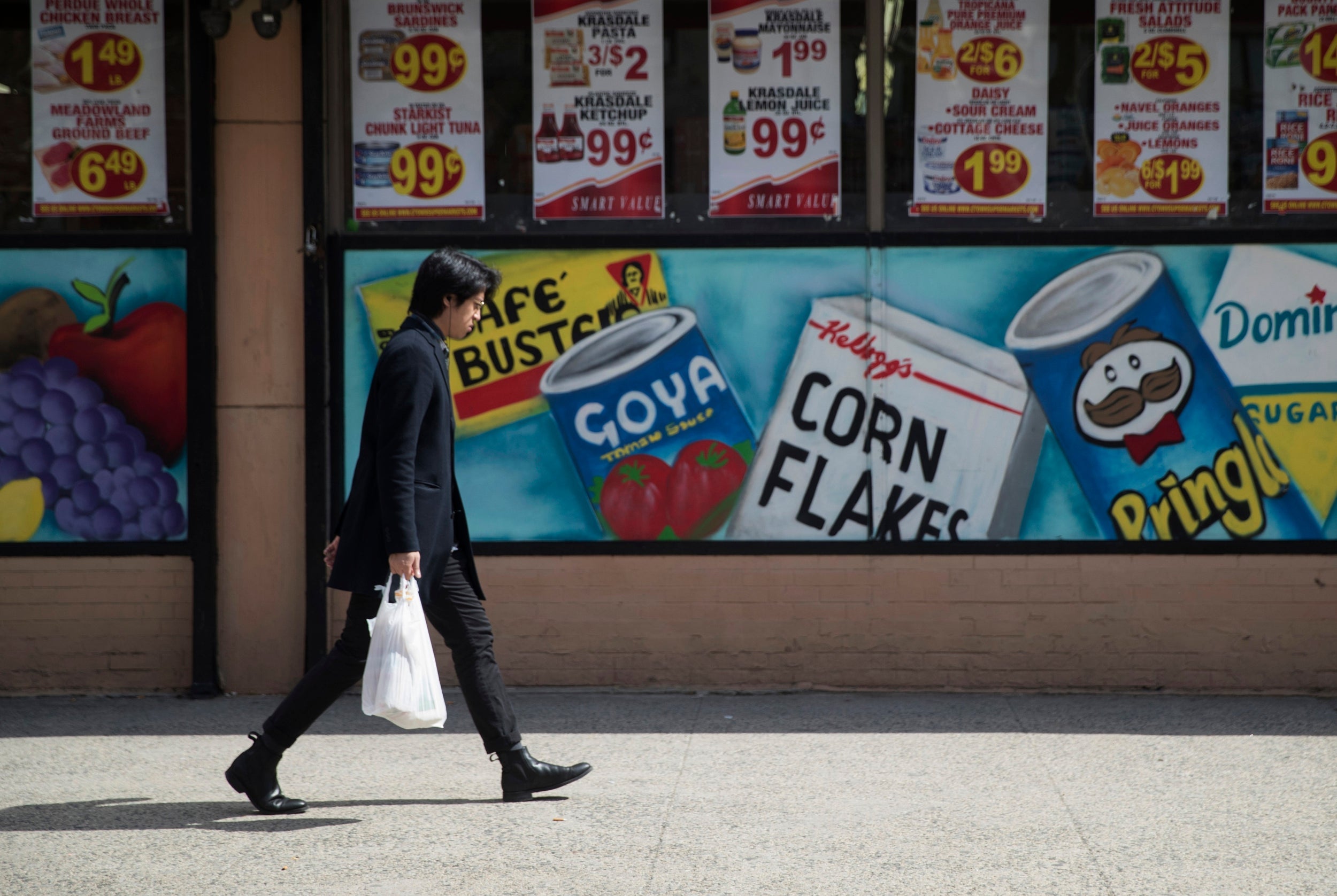 A man walking past a supermarket in East Village, Manhattan. New York is banning single-use plastic bags