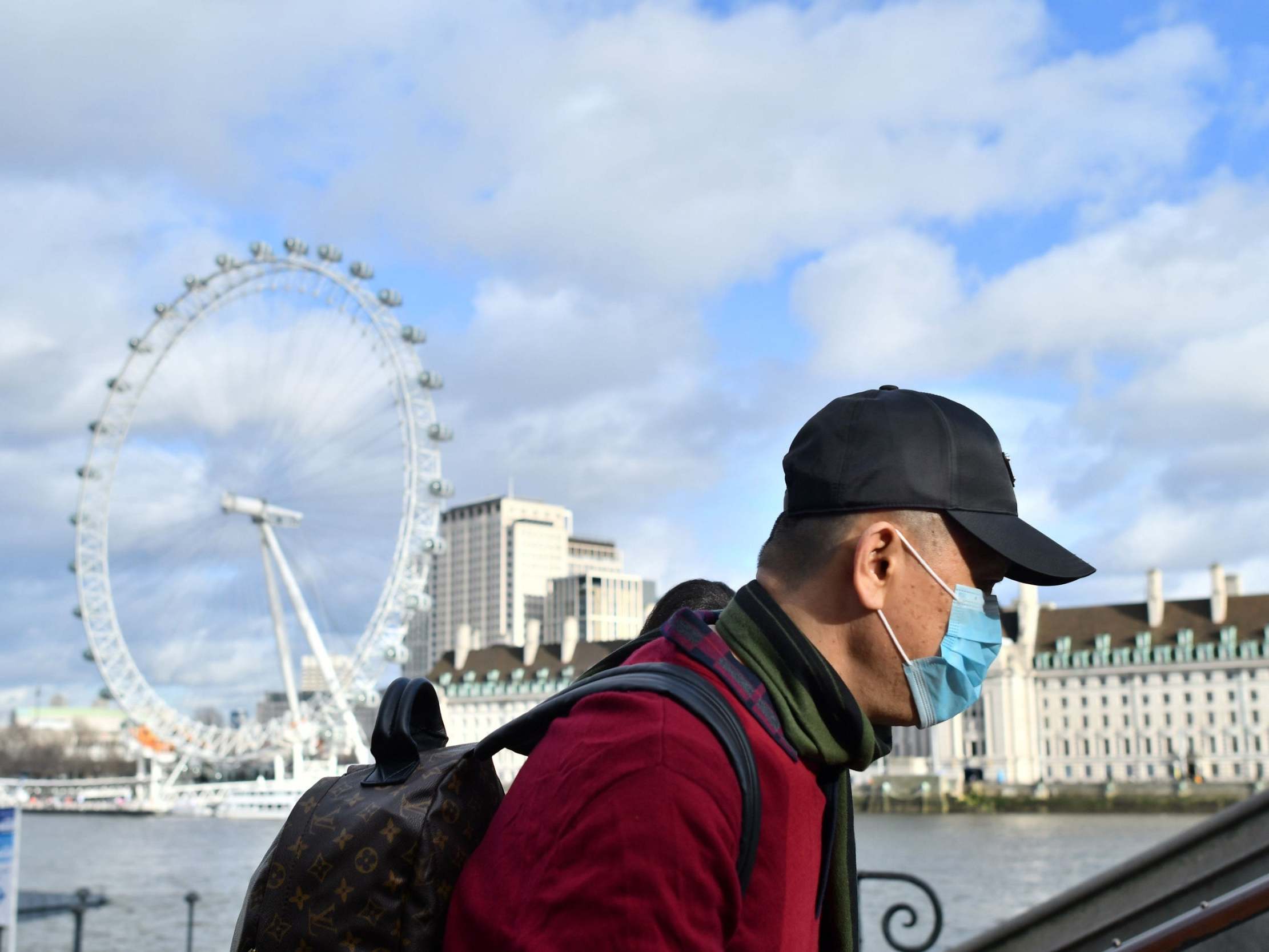 A man wears a face mask as he walks along the Thames embankment in central London