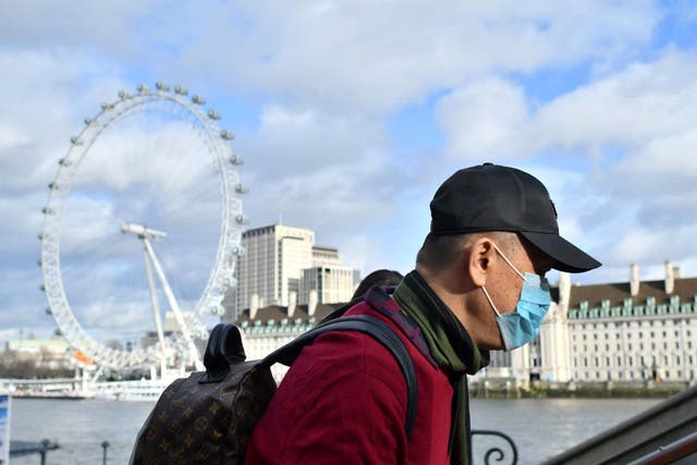 A man wears a face mask as he walks along the Thames embankment in central London