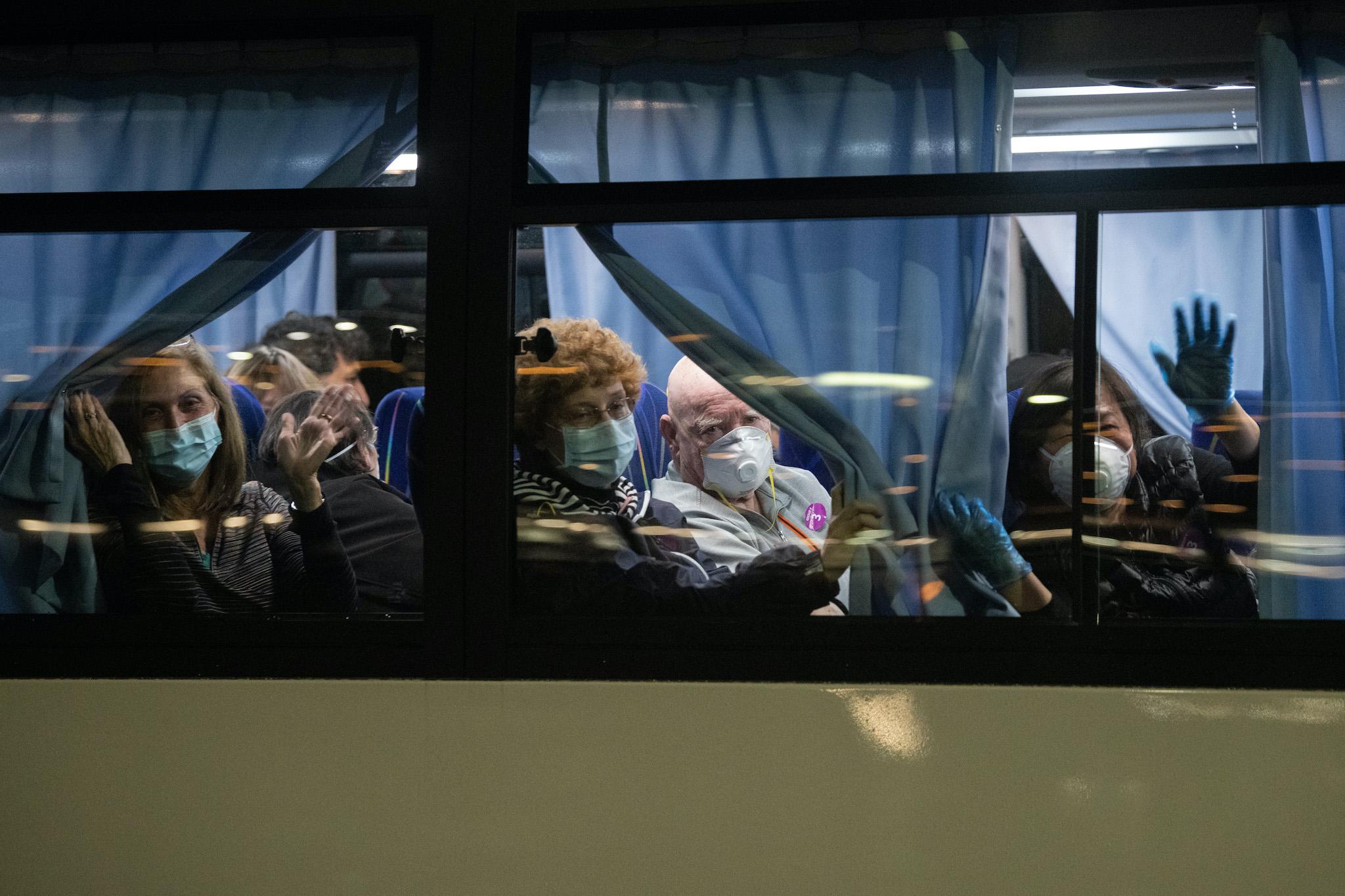 American citizens wave from a bus as they leave the quarantined Diamond Princess cruise ship at Daikoku Pier to be repatriated to the United States on February 17, 2020 in Yokohama, Japan